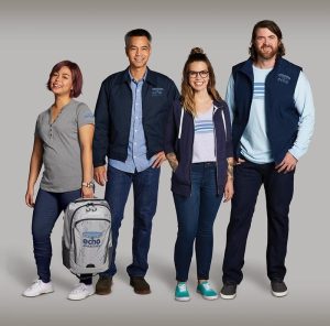 two women and two men wearing printed apparel. one woman is holding a printed backpack.